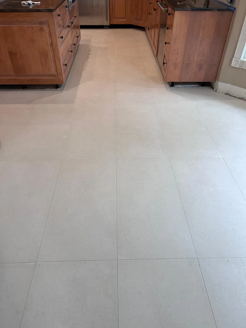 Light tile flooring between wood kitchen cabinets