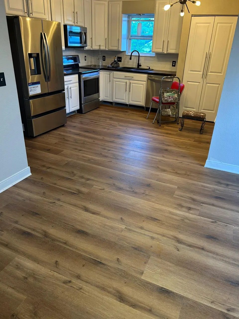 Brown plank flooring in a kitchen with stainless appliances